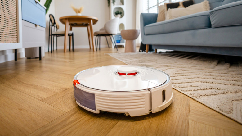 A robotic vacuum cleaning a hardwood floor in a living room