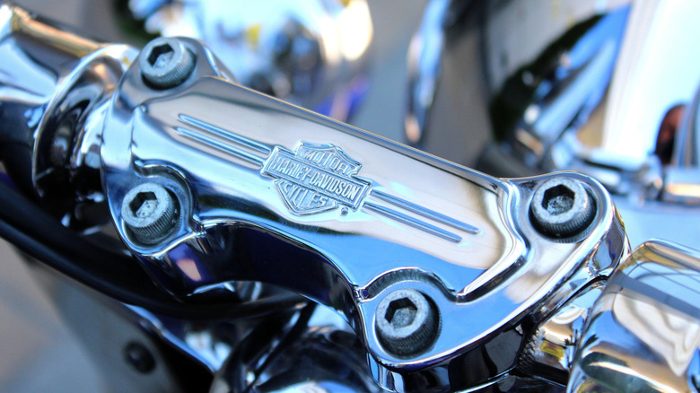 Close-up of Harley-Davidson emblem on motorcycle handlebars.