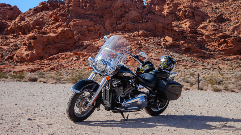 A Harley-Davidson motorcycle parked in the desert with red rocky mountains in the background