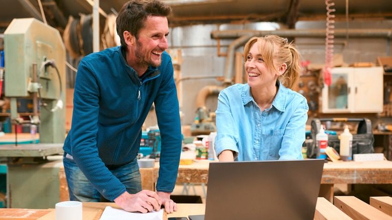 Two people in a woodshop using a laptop