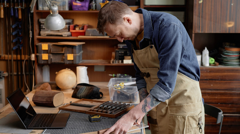 A person in a woodshop using a laptop