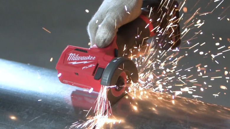 Person using Milwaukee M12 compact cut off tool on metal creating many sparks