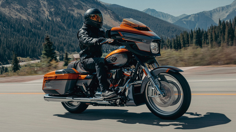 A person riding Harley-Davidson Street Glide on a rural road with mountains in the background.