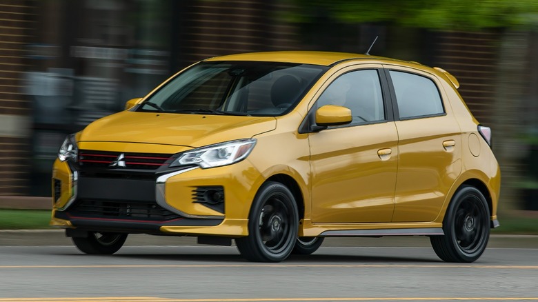 a yellow Mitsubishi Mirage driving on a road