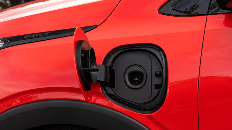 Close-up of the NACS charging port on a red 2027 Chevrolet Bolt
