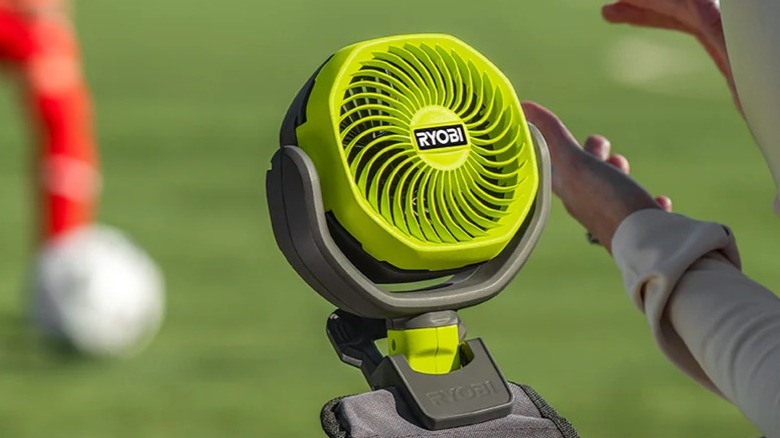 A person using a Ryobi fan outside.
