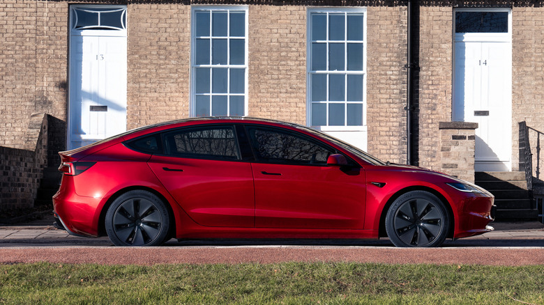 Red Tesla Model 3 parked in front of a building