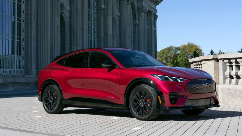 A 2025 red Ford Mach-E parked in front of a large, historic building