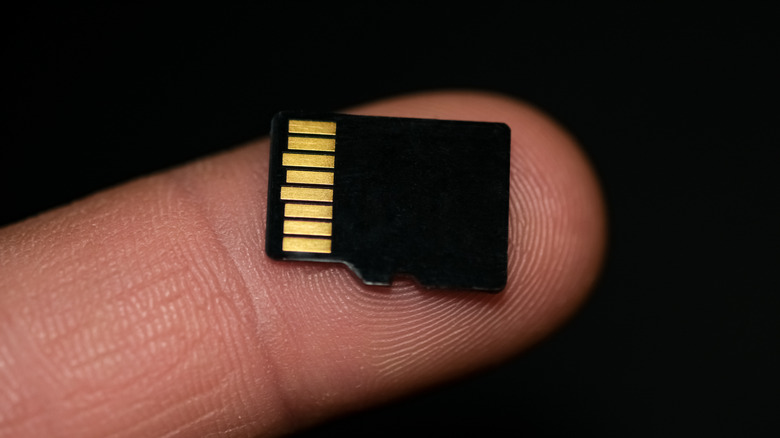 Microsd card on human finger on black background