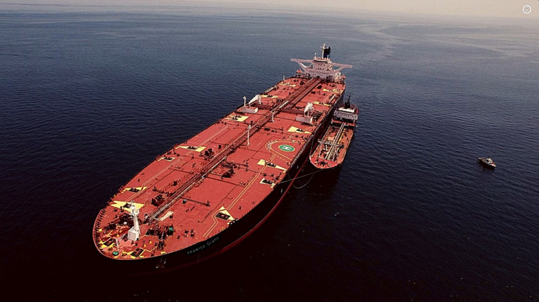Image of the Seawise Giant at sea with a smaller boat moored next to it and a tug boat nearby.