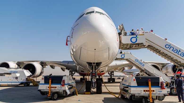 Front view of Airbus A380 aircraft nose with boarding stairs and ground handling equipment during Dubai Airshow 2025