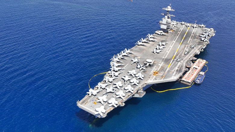 Aerial drone photo of USS Gerald R. Ford latest technology nuclear powered aircraft carrier anchored in deep blue open ocean sea