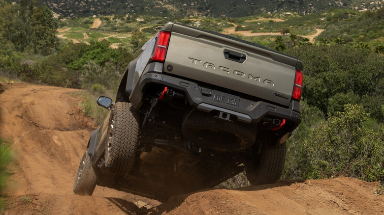 Rear 3/4 view of bronze Toyota Tacoma on a hilly off-road dirt trail