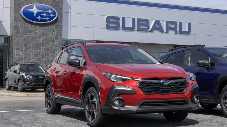 A red Subaru Crosstrek outside a Subaru dealer showroom.