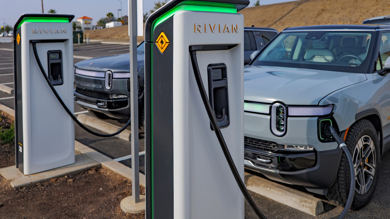 A pair of Rivian R1S SUVs plugged into an electric charging station