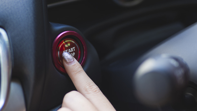 Person pressing the push start button on their car