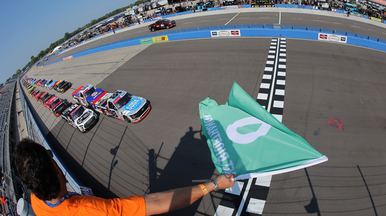 Trucks approach the checkered starting line to kick off the 2024 NASCAR Craftsman Truck Series race at Milwaukee Mile.