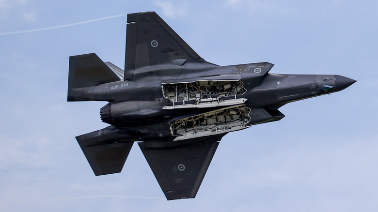 View of the underside of an F-35 fighter jet in the air.