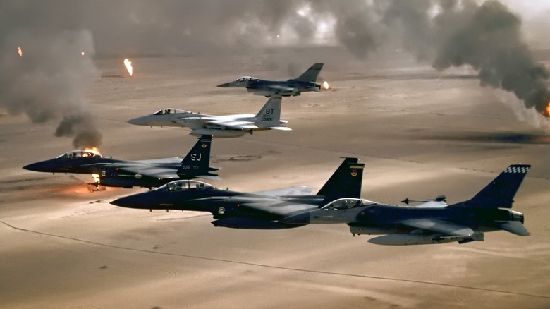 A wing of F-16s flying over the Iraqi desert as oil wells burn
