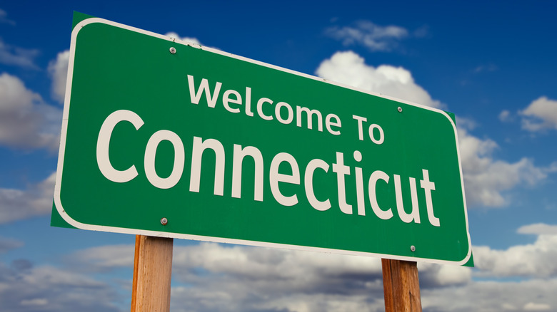 A roadside Connecticut welcome sign against a blue sky.
