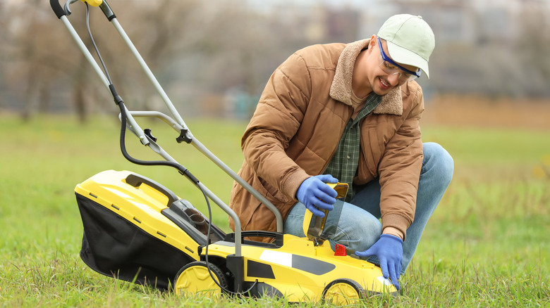 man adjusting lawn mower outside