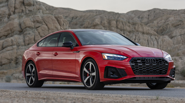 A red Audi A5 parked in front of a rocky cliff