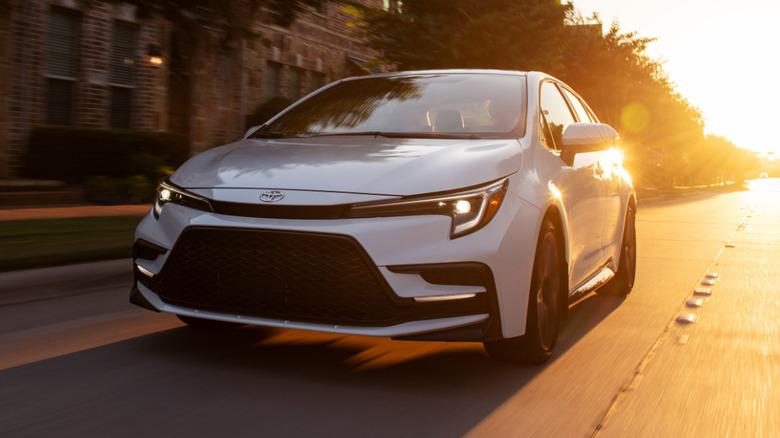 2026 white Toyota Corolla XSE driving down the street at sunset