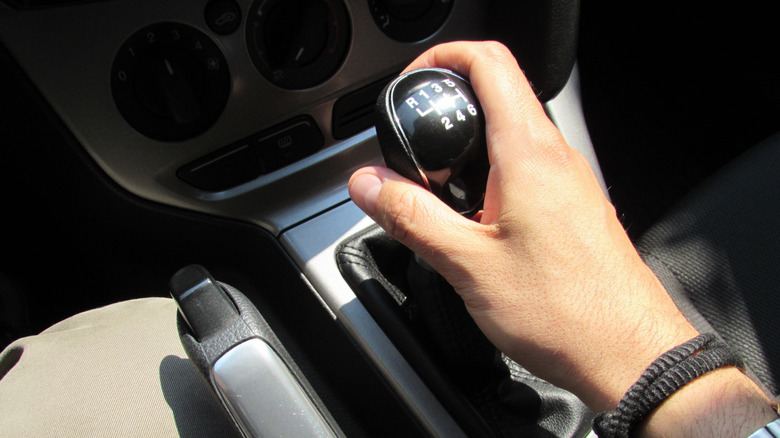 A close-up of a person holding a car transmission gear lever.