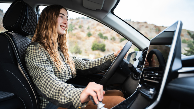 Close shot of female driver in car, shifting manual transmission