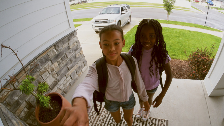 Doorbell camera capturing the arrival of two young children at the front door.
