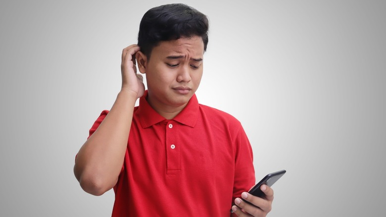 man confused staring at phone
