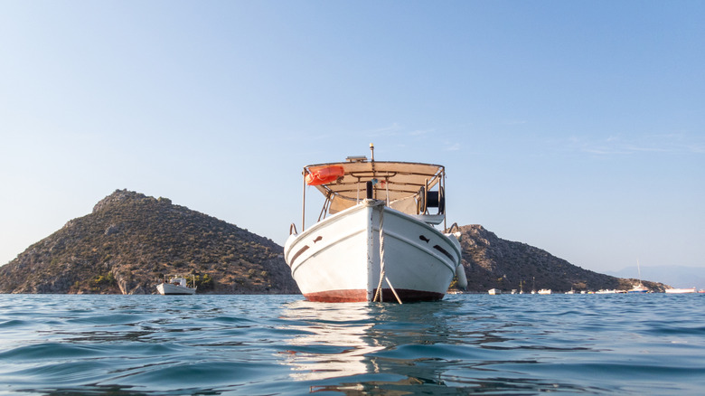A white fishing boat on a sunny day with two hills behind it