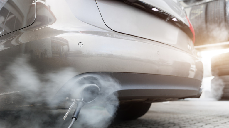 A car exhaust pipe emits dense smoke during emission test