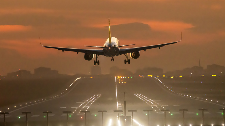 A commercial airplane landing at dusk.