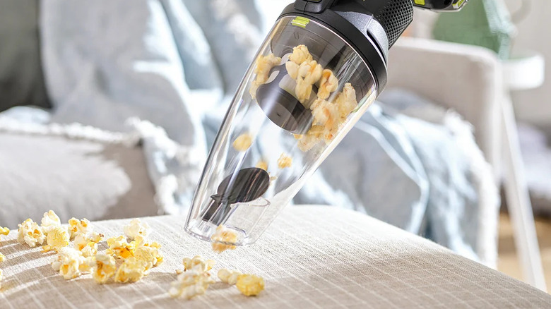 A close-up shot of a person cleaning up spilled popcorn with Ryobi hand vacuum