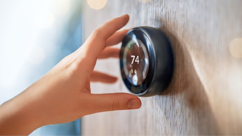 Person reaching to adjust their thermostat settings