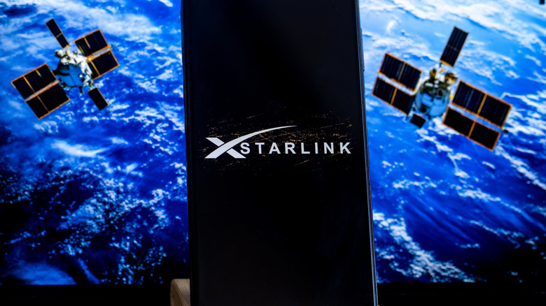 Starlink logo is sharp displayed in the foreground, while the stylite in displayed on computer in the background