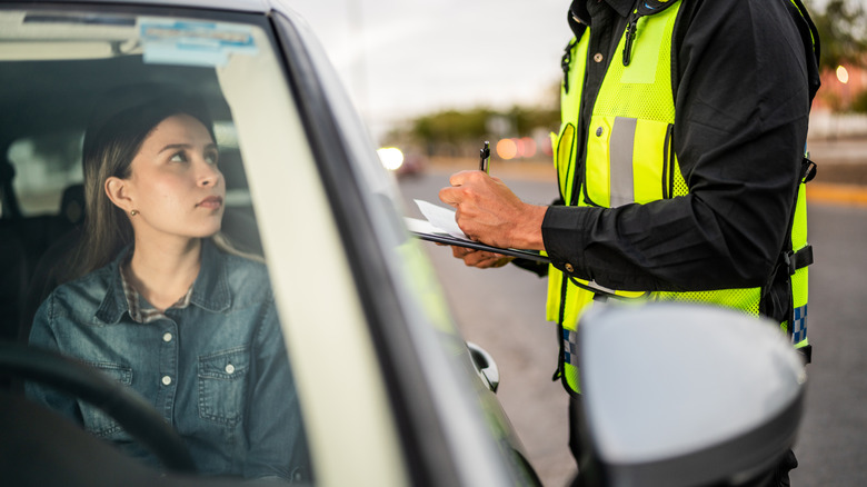 A driver being given a ticket by law enforcement.