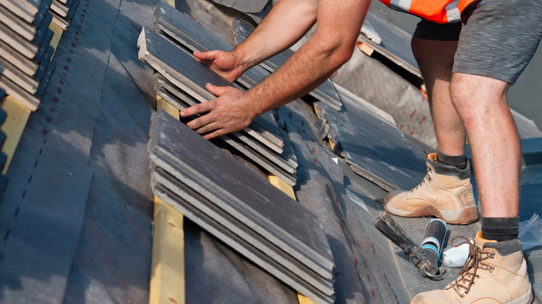 A roofer refitting roof tiles