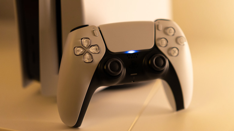 PS5 controller next to the console on a plain white surface