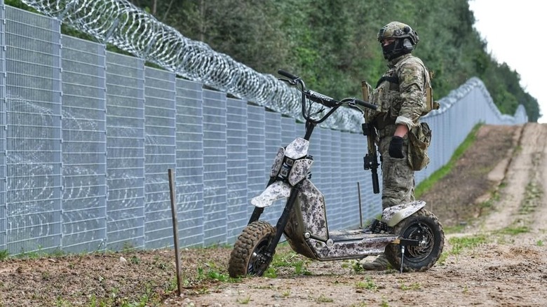 A border patrol soldier standing next to a Mosphera e-scooter made by Global Wolf Motors.