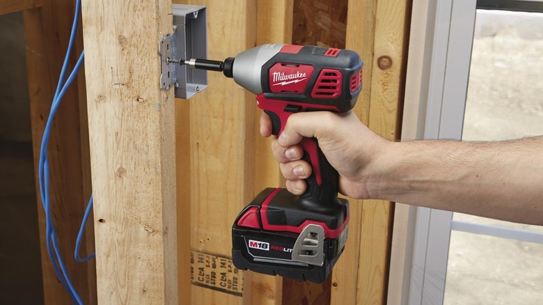 A person using a Milwaukee hex impact driver on wood.