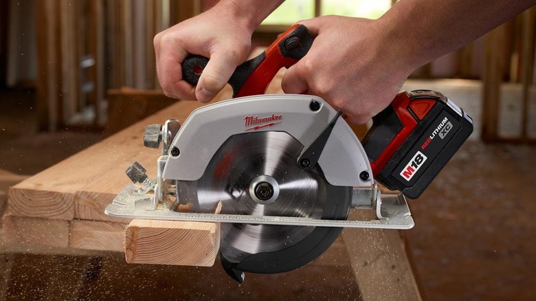 A person using a Milwaukee circular saw on wood.