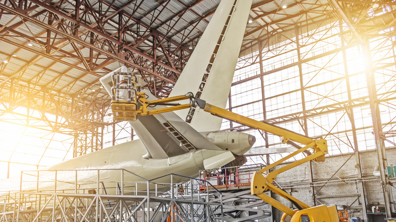 Worker on crane servicing airplane