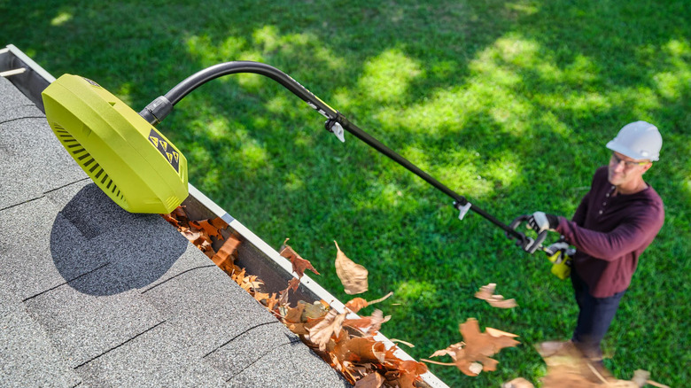 person cleaning gutter with ryobi attachment