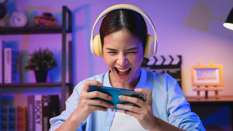 Girl playing game on her phone while wearing headphones