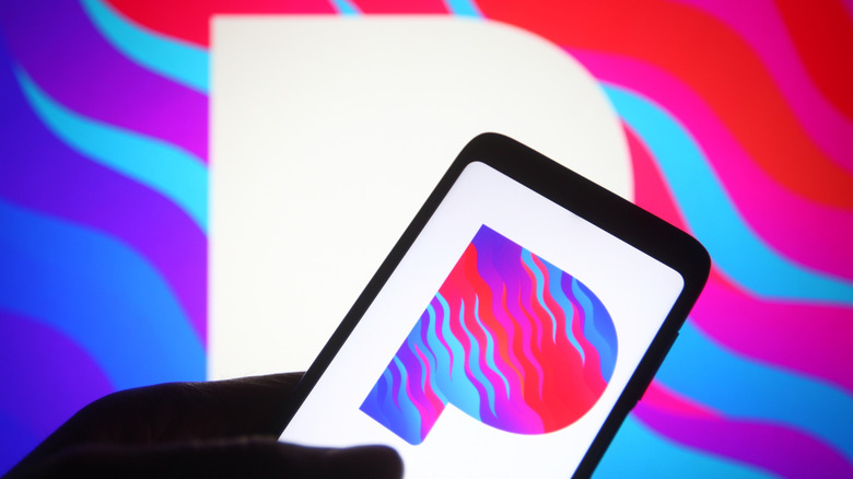 A smartphone showing the Pandora logo in front of a larger logo.