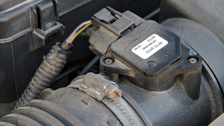 Close up shot of a mass air filter sensor in a car thats covered in dust.