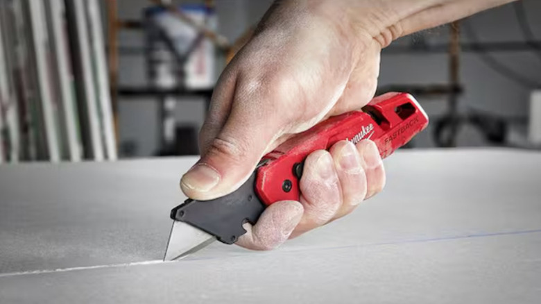 Man using Milwaukee press and flip box cutter on surface