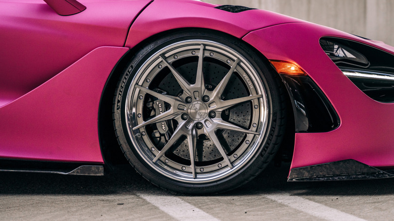 Close-up of large rim and low-profile tire on a pink McLaren.